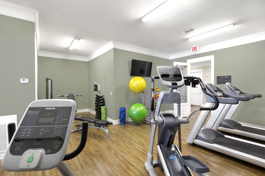 a gym with cardio equipment and a yellow ball