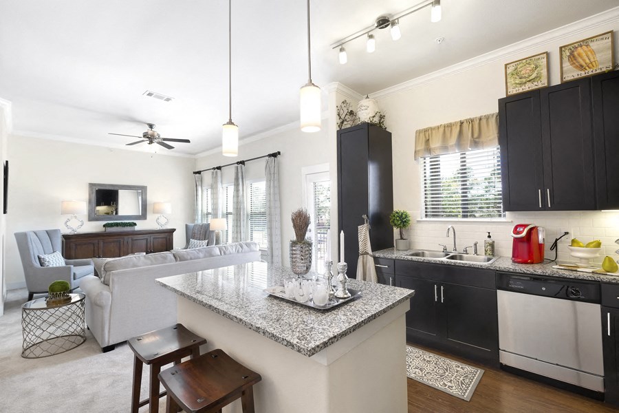 a kitchen and living room with black cabinets and a counter top