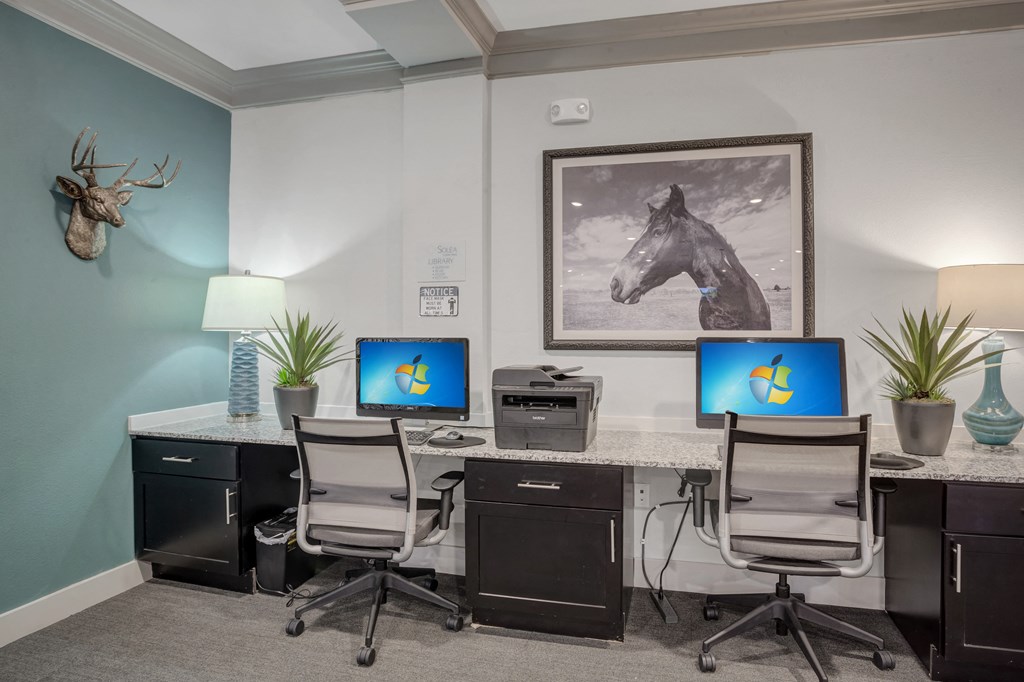 an office with three computers on a desk and a painting of a horse