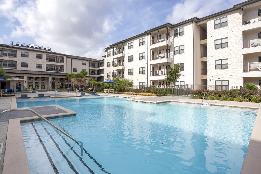 a large swimming pool in front of an apartment building