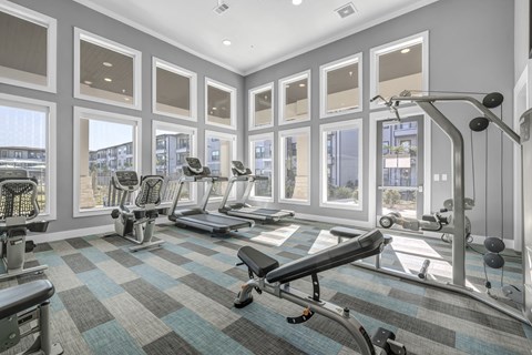 a gym with fitness machines and equipment at a senior apartment community