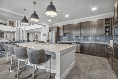 a communal clubhouse kitchen with a large island and chairs at a senior apartment community