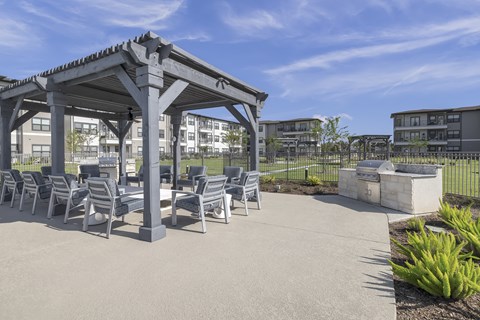 a poolside sitting area under a wooden pergola at a senior apartment community