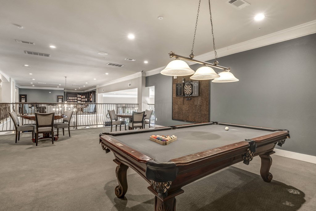 a pool table in a living room with a dining room in the background
