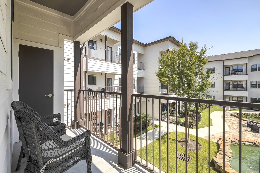 a balcony with a chair overlooking an apartment building