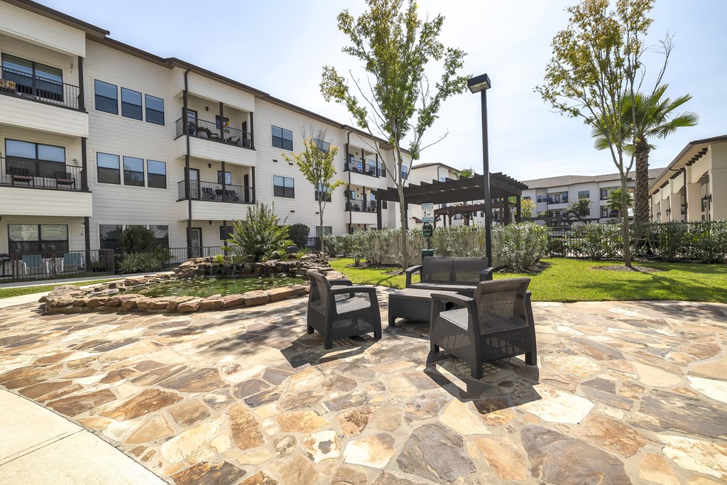 a patio with two chairs and a table in front of an apartment building