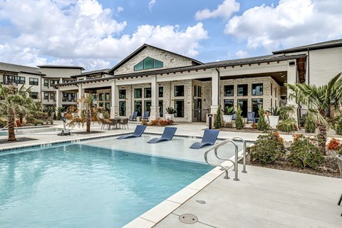 a swimming pool with blue chairs and a building in the background