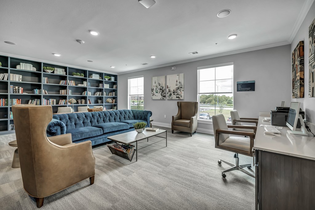 a library with a blue couch and a desk and chairs