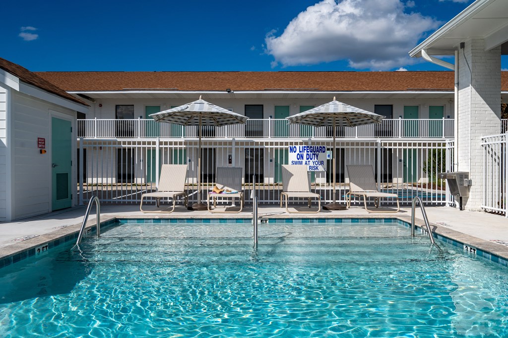 a resort style pool with chairs and umbrellas in front of a building at The Teale Navy Yard, North Charleston, South Carolina