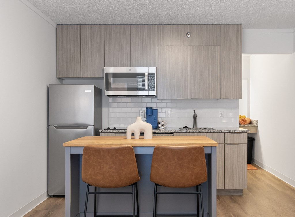 a kitchen with stainless steel appliances and a island with two chairs at The Teale Navy Yard, North Charleston, SC, 29405