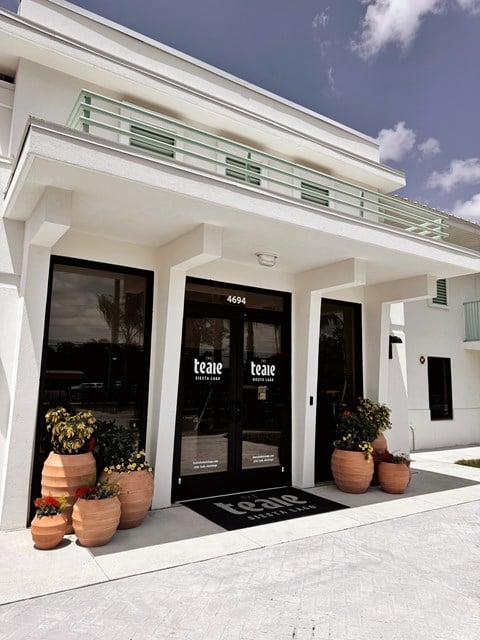 The front of a white building with a black door and windows. at The Teale Siesta Lago in Kissimmee, FL, 34746