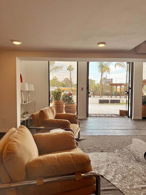 A living room with a row of couches and a view of the outdoors through the sliding glass doors.