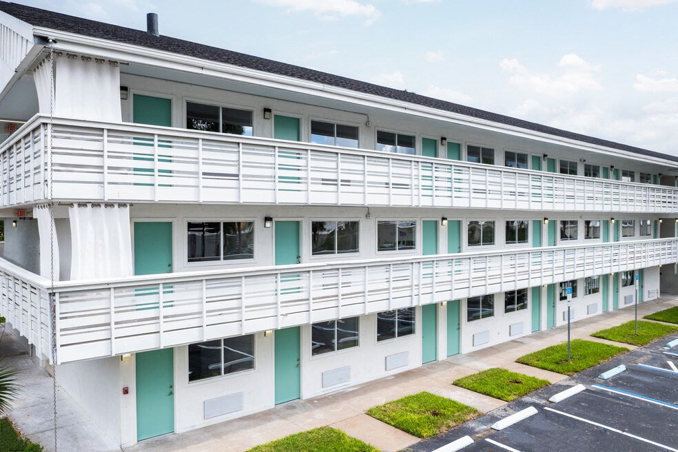 an exterior view of a white building with green doors and railings