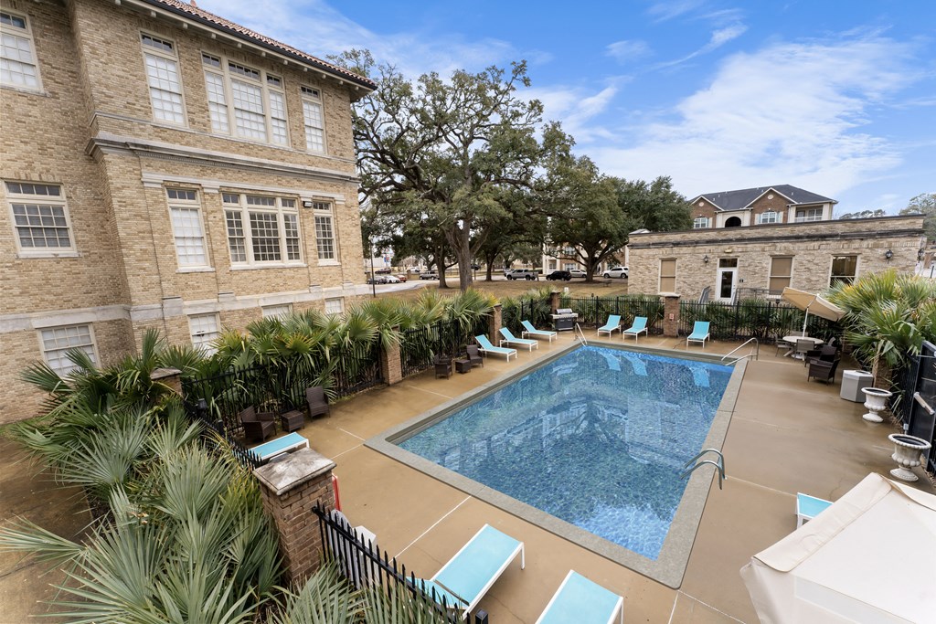 a swimming pool with lounge chairs in front of a building