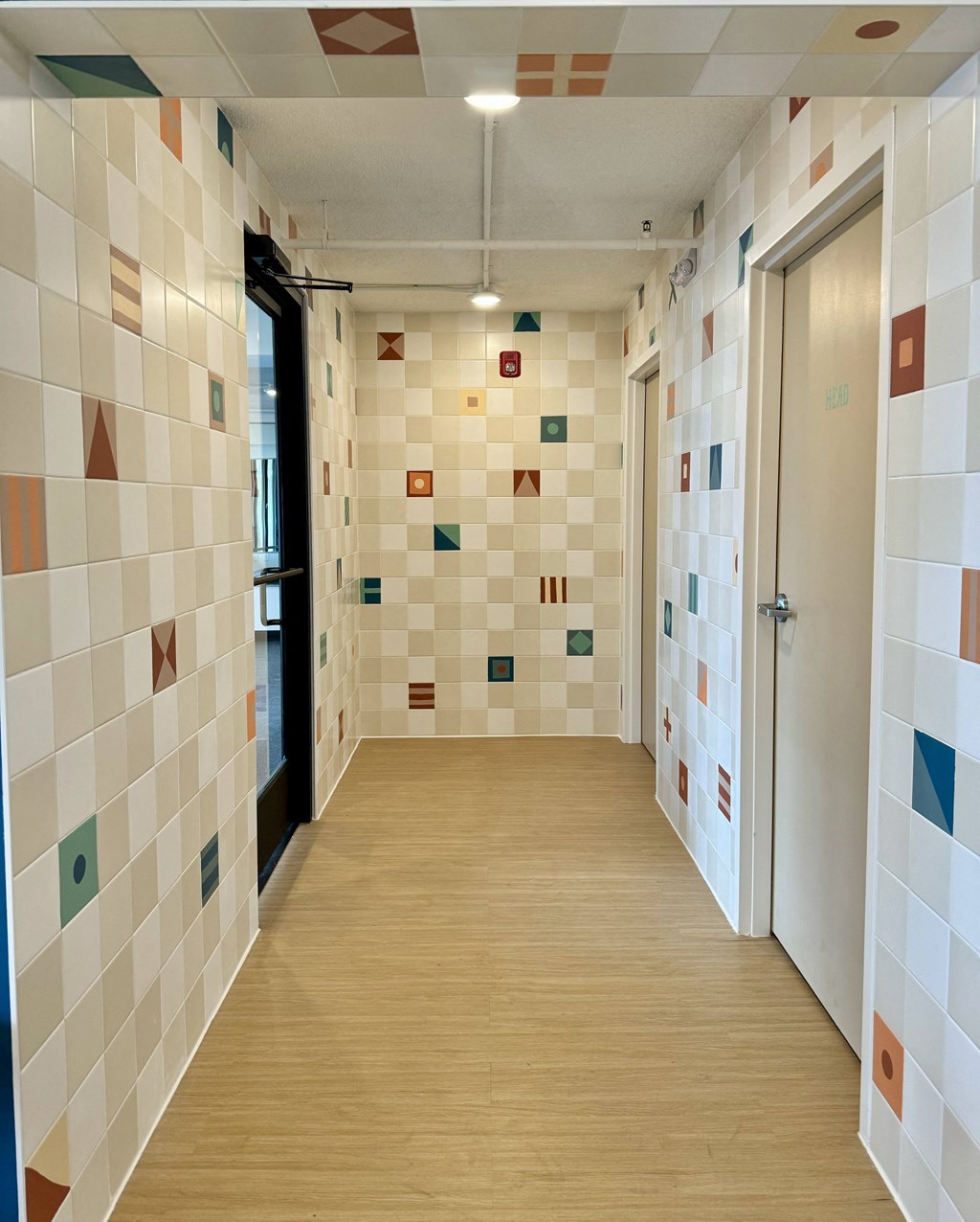 a hallway with a wood floor and tiles on the walls and a door at The Teale Navy Yard, North Charleston, SC, 29405