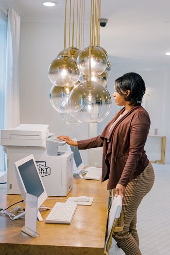 a woman standing in front of a desk with a printer and lights at The Roseberry, Columbia, 29223