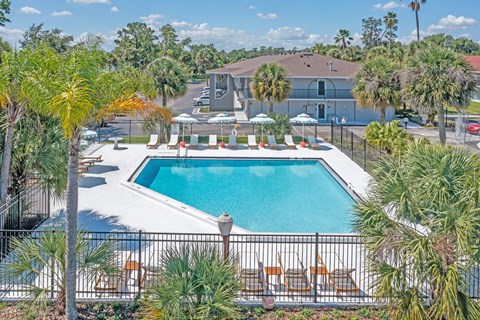 a swimming pool with chairs around it and a building in the background