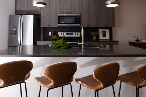 a kitchen with a counter and chairs and a refrigerator