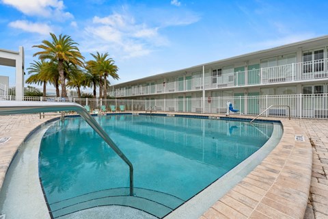 A swimming pool in front of a building with palm trees.at The Teale New Haven Apartments, Melbourne, FL, 32904