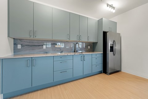 A kitchen with blue cabinets and a black refrigerator.