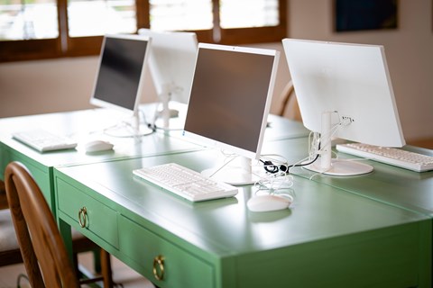 Three computer monitors are on a green desk.