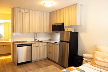 a small kitchen with a refrigerator and sink in a hotel room at The Teale, Kissimmee, FL, 34746