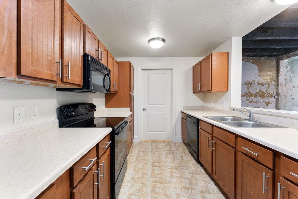 an empty kitchen with wood cabinets and black appliances