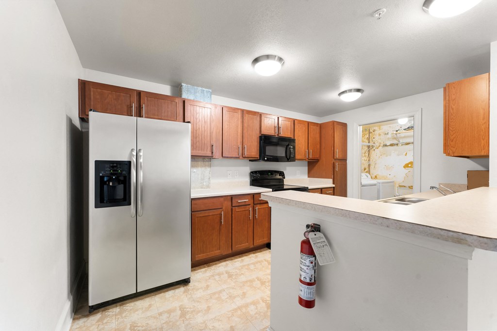 full kitchen with stainless steel appliances and white countertops with a bar with a bottle