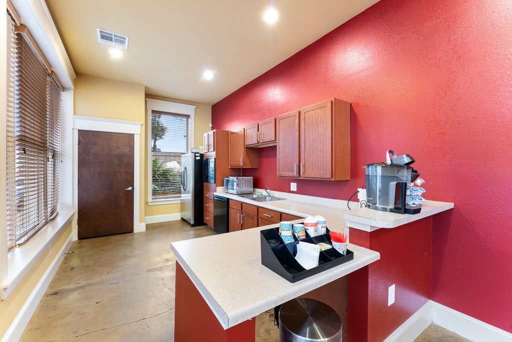 a kitchen with a red wall and a counter with drinks on it