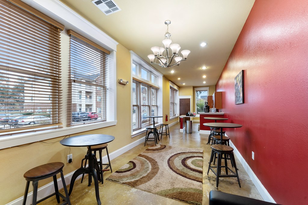 a dining area with tables and chairs and large windows