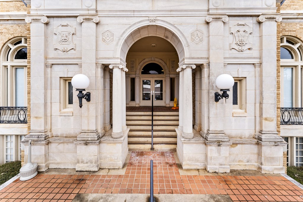 the front of a white building with stairs and an arch