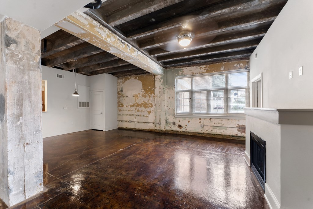 an empty living room with exposed brick walls and a fireplace
