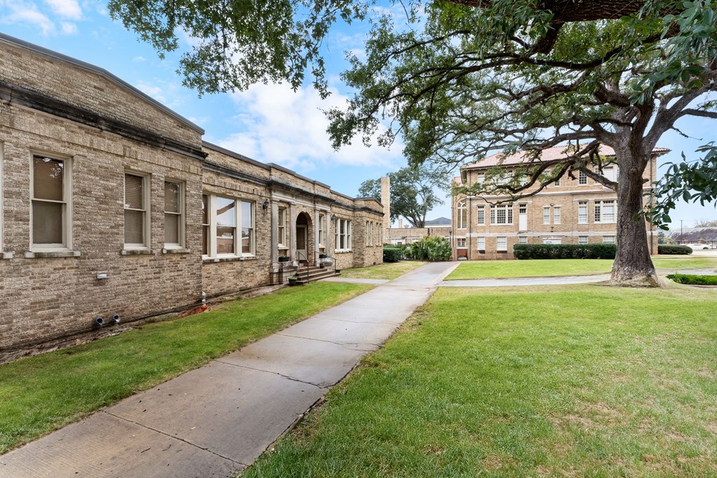 a sidewalk in front of two brick buildings and a tree