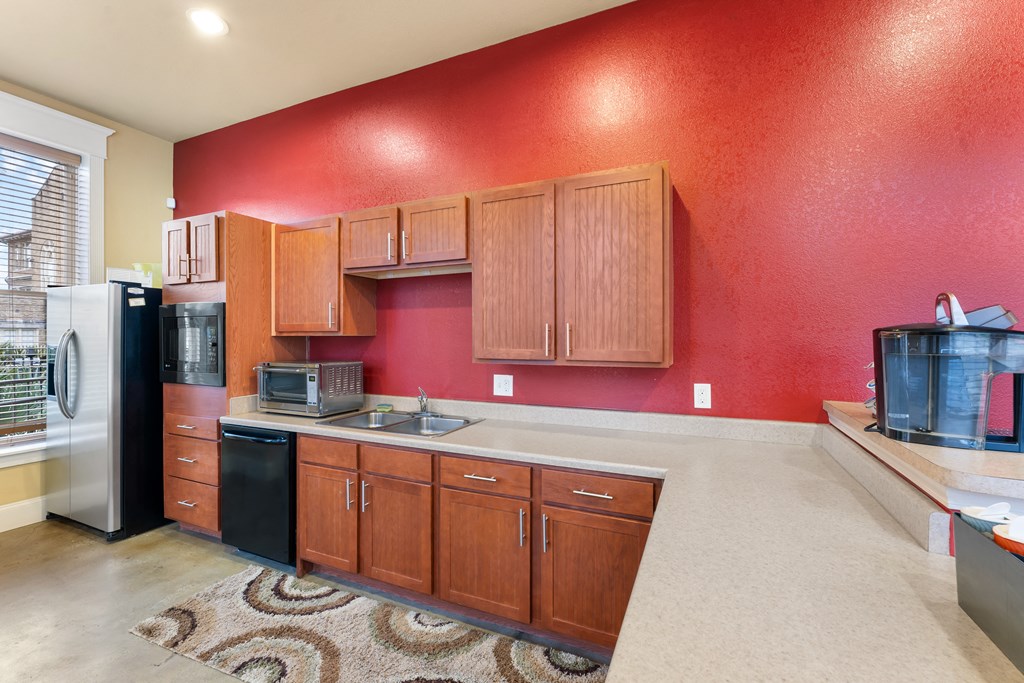 a kitchen with a red wall and a sink and a refrigerator