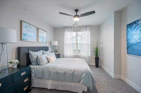 A bedroom with a bed, dresser, and ceiling fan.