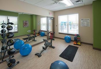 A gym room with exercise equipment and a mirror.