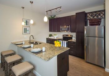 A kitchen with a granite countertop and stainless steel appliances.