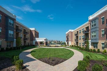 A sunny day at a residential complex with a green lawn and pathways.