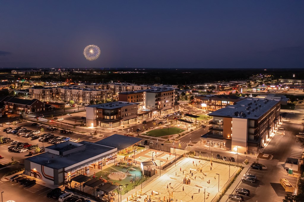 A nighttime view of a cityscape with a lit-up building and a firework display in the sky.