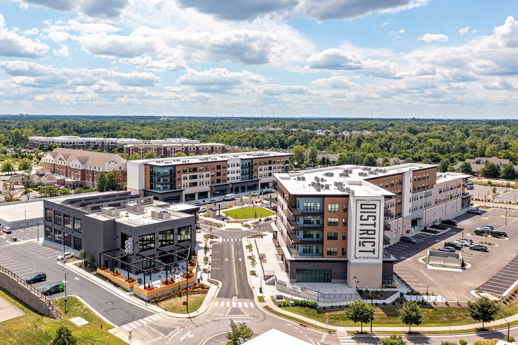 A large building with the word "DISTRICT" on it is surrounded by other buildings and a parking lot.