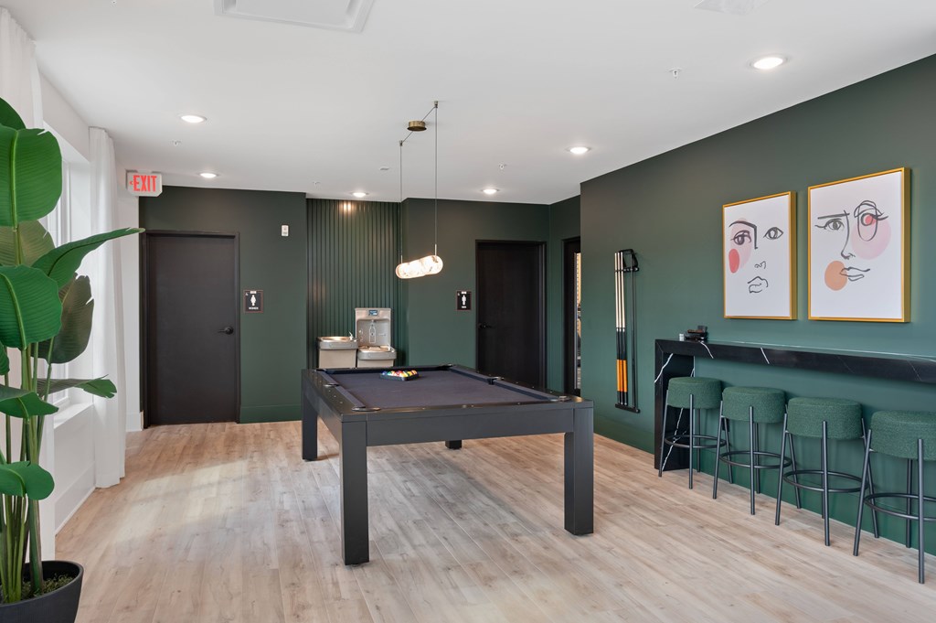 A pool table in a room with green walls and a bar area.