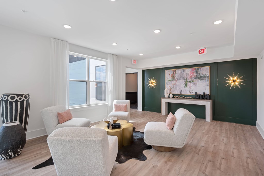 A living room with a white sofa, a white chair, a white coffee table, a black and white sculpture, a green wall, and a white fireplace.