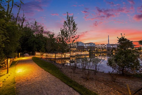 A pathway with a view of a lake and buildings in the distance.