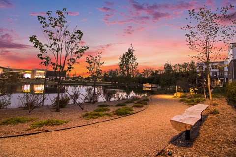 A park bench sits on a gravel path next to a body of water.