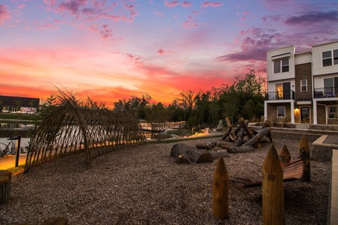 A beautiful sunset view of a beachfront property with a sand pit and wooden posts.