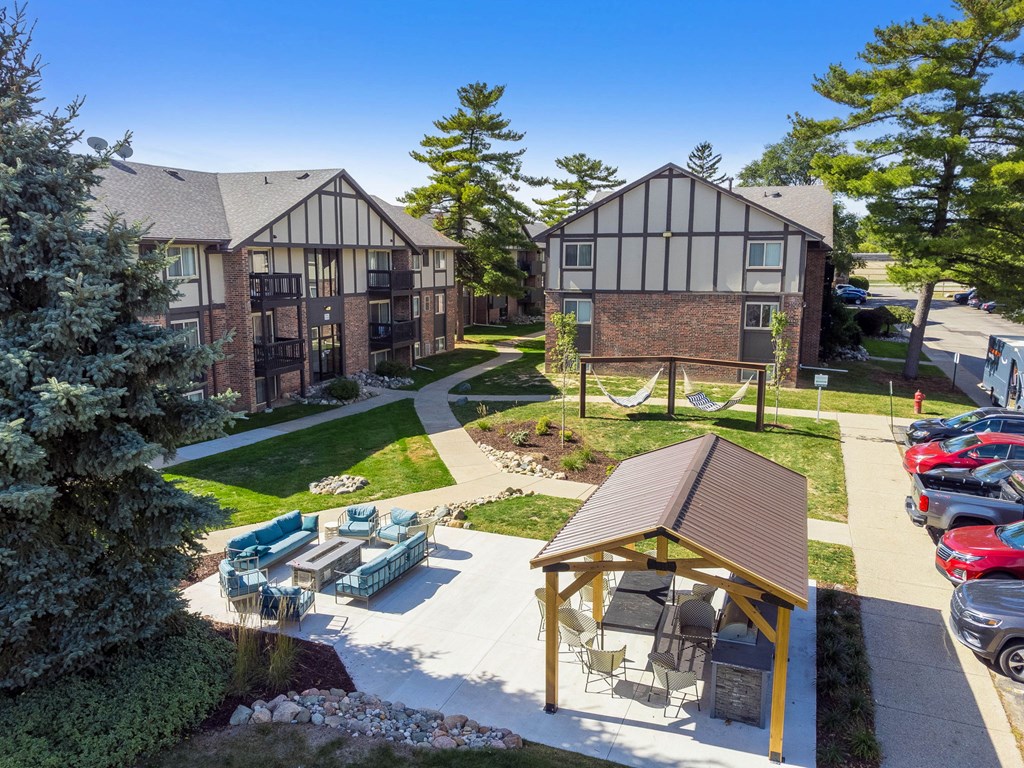 A small pavilion is surrounded by a grassy area and a parking lot.