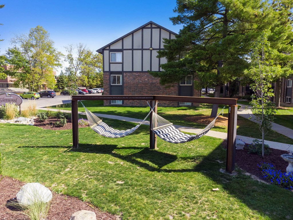 A hammock is strung between two wooden posts in a grassy area.