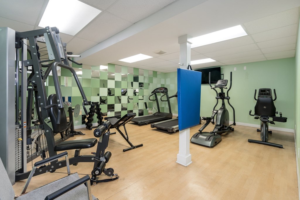 A gym with a variety of equipment including treadmills, weights, and exercise machines.