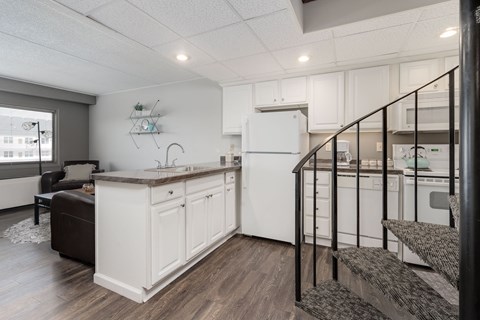 A kitchen with white cabinets and a black railing.
