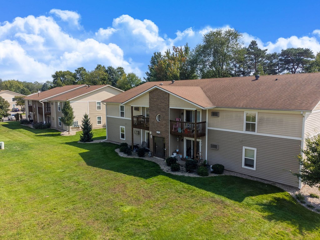 A row of houses with green lawns and trees in the background.